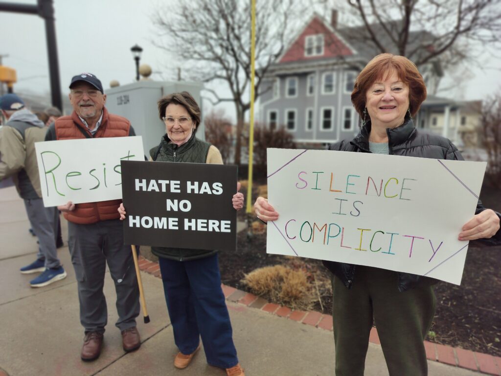 Protests with signs that say "hate has no home here" and "silence is complicity"
