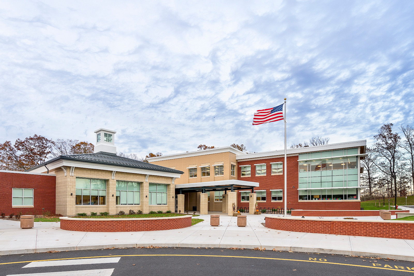 A picture of moser elementary school under a blue sky, with an American flag waving in the foreground