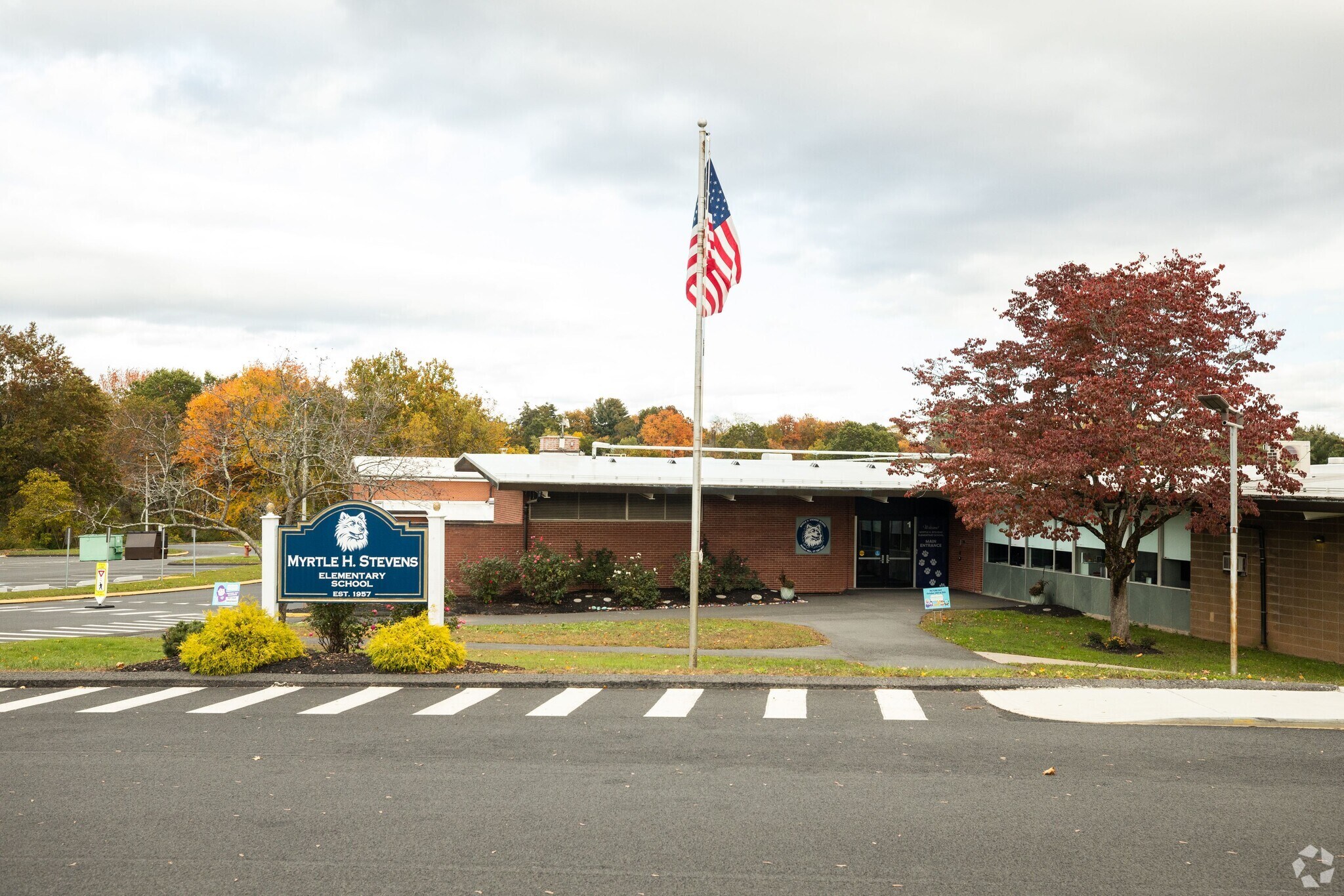 a school building, a flag pole with the American flag in the foreground