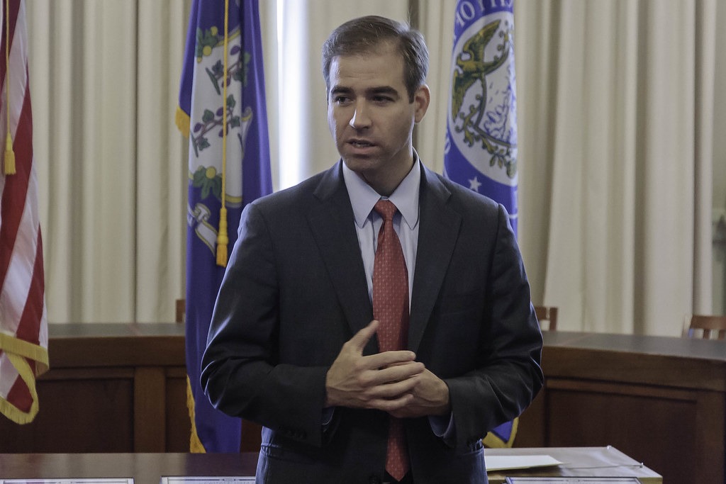A man in a suit in front of flags